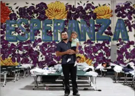  ?? MARK LAMBIE — THE EL PASO TIMES VIA AP, FILE ?? A Guatemalan man poses for a photo with his young son at the new Casa del Refugiado in east El Paso, Texas. Behind him is a full-wall mural which reads Esperanza, or hope. A federal appeals court ruling will allow the Trump administra­tion to begin rejecting asylum at some parts of the U.S.- Mexico border for migrants who arrived after transiting through a third country.