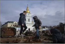  ?? EVGENIY MALOLETKA — THE ASSOCIATED PRESS ?? Children stand atop of a destroyed Russian vehicle in the city center of Kyiv, Ukraine, on Thursday.