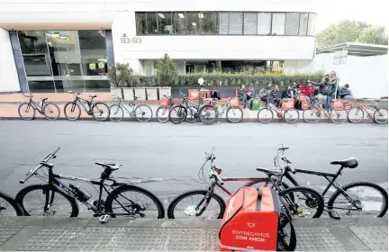  ??  ?? Bicycle couriers wait for messages from the Rappi applicatio­n to take orders to clients in Bogota, Colombia, a Monday, July 8.