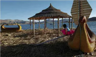  ??  ?? Menina brinca em barco feito com totora, junco comum na ilha de Uros, no lago Titicaca