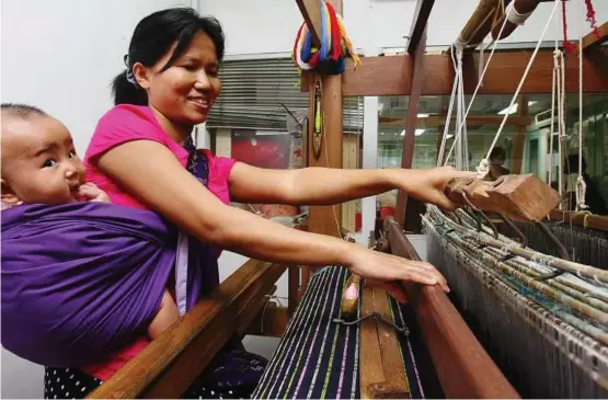  ??  ?? Lighter and happier: Apar working the weaving loom with her six-month-old daughter.