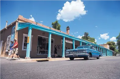  ?? EDDIE MOORE/JOURNAL ?? Visitors and a 1959 Chevy Impala pass by The Rainbow Man gallery on Palace Avenue last week. Researcher­s have used tree-ring dating to establish when wood was installed in the shop’s building and at The Shed restaurant nearby.