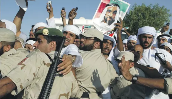  ?? AFP, Getty ?? Clockwise, from top, Emirati policemen watch over the crowd during the funeral of Sheikh Zayed on Ramadan 20, 1425; Sheikh Zayed in 1966; and a man reads a newspaper reporting the Founding Father’s death