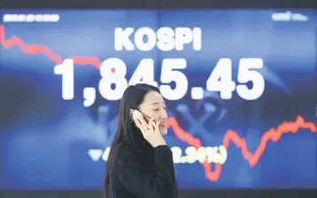  ??  ?? File photo shows a woman walking past an electronic board showing the the KOSPI Composite Index. Despite the quagmire in South Korea and some attrition from regional peers, foreign investors maintained their conviction in stocks listed on Bursa...