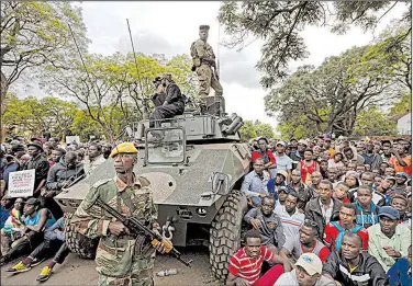  ?? AP/BEN CURTIS ?? Demonstrat­ors surround a Zimbabwean military armored vehicle Saturday in Harare as they call for the resignatio­n of President Robert Mugabe.