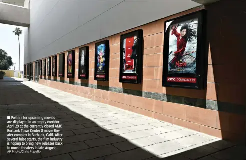  ?? AP Photo/Chris Pizzello ?? ■ Posters for upcoming movies are displayed in an empty corridor April 29 at the currently closed AMC Burbank Town Center 8 movie theater complex in Burbank, Calif. After several false starts, the film industry is hoping to bring new releases back to movie theaters in late August.