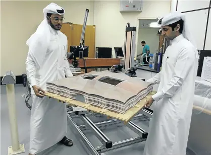  ?? Picture: REUTERS ?? GAME-CHANGER: Mechanical engineers Abdullah Mojeb Aldar and Fahad al-Musala move a 3D-printed model of Qatar’s Al Bayt stadium, which will host a World Cup semifinal in 2022, at a laboratory at Qatar University in Doha