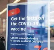  ?? SERGIO FLORES/GETTY ?? A sign about the COVID-19 vaccine is displayed on the window of a Walgreens.