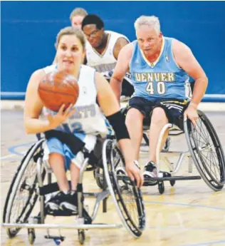  ??  ?? Retired Navy Lt. Rickey Bennett, right, chases Christina Schwab during a Denver Rolling Nuggets wheelchair basketball team practice June 26. Karl Gehring, The Denver Post