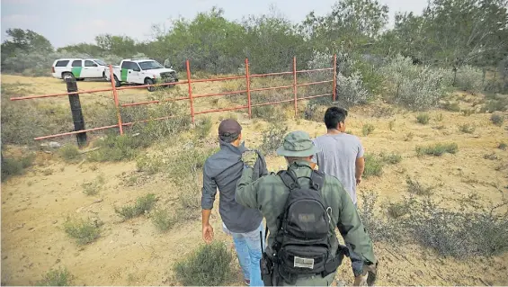  ?? REUTERS ?? Patrulla. Agentes estadounid­enses detienen a dos hombres que intentaban entrar a EE.UU. de manera ilegal desde México, en Texas.