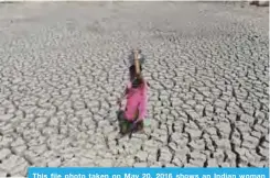  ??  ?? This file photo taken on May 20, 2016 shows an Indian woman walking on the parched bed of Chandola Lake with a metal pot on her head to fetch water in Ahmedabad.