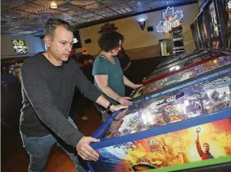  ?? KAREN SCHIELY/AKRON BEACON JOURNAL/TNS ?? Joe Bertolini (left) and Pamela Sams play pinball during a meeting of the Stonehedge Pinball League at Stonehedge in January in Akron.