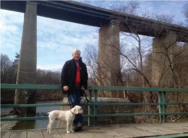  ?? SHAWN MICALLEF PHOTOS FOR THE TORONTO STAR ?? David Miller with his dog, Jimmy, standing on the footbridge over the Humber River by the CP railway line.