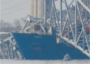  ?? MATT ROURKE/AP ?? A container rests against wreckage of the Francis Scott Key Bridge on March 26 as seen from Sparrows Point, Maryland. The ship rammed into the major bridge in Baltimore, causing it to collapse in a matter of seconds and creating a terrifying scene as several vehicles plunged into the chilly river below.