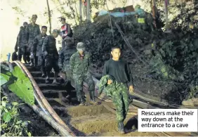  ??  ?? Rescuers make their way down at the entrance to a cave