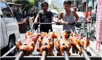 ?? THE FAMOUS LA LOMA LECHON. PNA photo ?? Workers push a cart loaded with ready-for-display lechon as La Loma, Quezon City celebrated its Lechon Festival 2019 over the week. The festivitie­s included a lechon float parade, street boodle fight, a fireworks display, and a culinary competitio­n where the main ingredient was lechon, a Filipino dish popular for its crispy skin and juicy meat. -