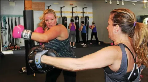  ?? MICHILEA PATTERSON — DIGITAL FIRST MEDIA ?? Christa Costello does a boxing combinatio­n with the help of her partner Megan Lewis during a boxing boot camp class at Ignite Fitness Studio in West Vincent.