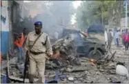  ?? FARAH ABDI WARSAMEH — THE ASSOCIATED PRESS ?? A Somali soldier walks near wreckage of vehicles after a car bomb was detonated in Mogadishu, Somalia Saturday.