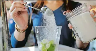  ?? ALAN DIAZ/AP PHOTO ?? Bartender Rafaella Demelo pours two bar spoons of sugar onto 1.5 ounces of Leblon and half a lime cut in cubes as she prepares a caipirinha at Bulla, a bar in Coral Gables, Fla.