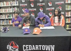  ??  ?? Taji Hudson and Kobe Pryor were flanked by their mothers as they signed the paperwork to head off to East Carolina and Clemson during a signing day celebratio­n at Cedartown High School on Dec. 18.