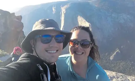  ?? SEAN MATTESON VIA AP ?? TRAGIC SHOT: Sean Matteson poses for a selfie with his girlfriend Drea Rose Laguillo, in Yosemite National Park, Calif., last week. The couple said Meenakshi Moorthy, seen in background at left, the pink-haired woman who fell to her death in Yosemite Park, accidental­ly appeared in two of their selfie photos