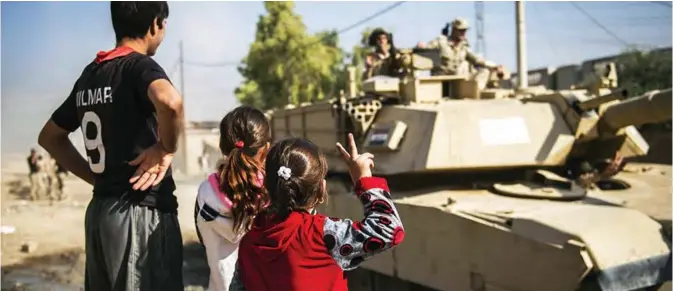  ?? — AFP ?? MOSUL: Iraqi children, one flashing the sign of victory, greet Iraqi army’s soldiers from the 9th armored division in the area of Ali Rash, adjacent to the eastern Al-Intissar neighborho­od of Mosul during a military operation to retake the main hub...