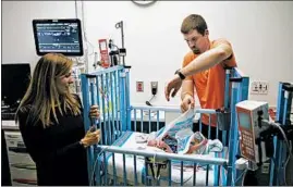  ??  ?? Andy Crutchfiel­d wraps a blanket around his son Kai while he and his wife, Brooke, visit their children in the neonatal intensive care unit.