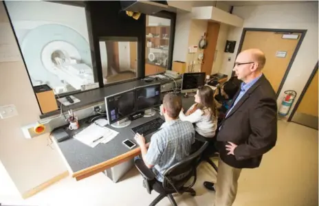  ?? GEOFF ROBINS FOR THE TORONTO STAR ?? Western University physicist Robert Bartha, right, uses a high-powered MRI machine to look for early signs of brain imbalances linked to Alzheimer’s.