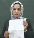  ?? — AFP ?? Kabul University student Zahra Faramarz shows her ID card or Tazkira registered to vote in the upcoming parliament­ary election.