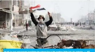  ?? — AFP ?? NAJAF: An Iraqi demonstrat­or brandishes the national flag in this southern Shiite holy city yesterday.