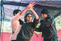  ?? New York Times ?? Neetu, right, helps students learn a hold during a selfdefenc­e training session run by the Delhi Police.