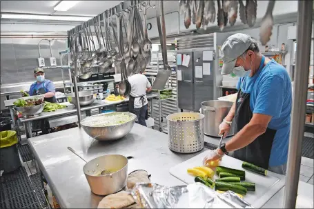  ?? SEAN D. ELLIOT/THE DAY ?? Volunteer Brian Carroll cuts zucchini and squash Wednesday in the kitchen at St. Vincent de Paul Place in Norwich.