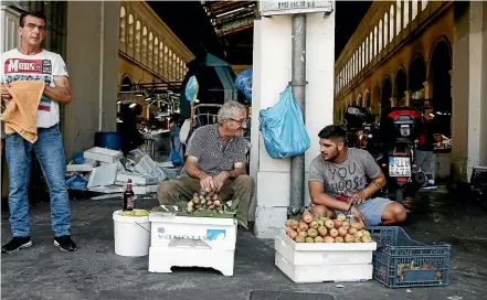  ?? AP ?? Street vendors talk outside the main fish market of Athens on the day that Greece’s eight-year crisis officially ended. Despite this deadline few Greeks see cause for celebratio­n.