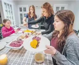  ?? PETER MCCABE/ THE GAZETTE ?? Annetta Black, second from right, serves dinner to daughters (from left) Eden, Sivan and Sidney Black-Rotchin. Sivan and Sidney are strict vegetarian­s.