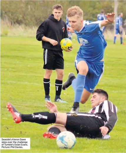  ??  ?? Seaside’s Kieron Dawe skips over the challenge of Tumble’s Osian Evans. Picture: Phil Davies.