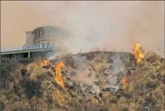  ?? Ringo H.W. Chiu/Associated Press ?? Firefighte­rs battle a brush fire Saturday on a hillside near a home in Burbank, Calif. Several hundred firefighte­rs worked to contain a blaze that chewed through brush-covered mountains, prompting evacuation orders for homes in Los Angeles, Burbank and...