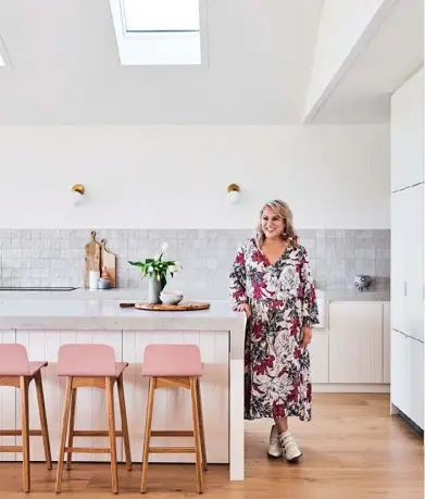  ??  ?? KITCHEN A magnet for Georgie, pictured top, and the family’s regular stream of guests, the kitchen and casual dining zone is further proof that white and grey – with pretty pops of none other than blush pink – form a match made in interiors heaven. The hardy Caesarston­e benchtops in Noble Grey are offset by the delicate Mallorca grey splashback tiles from National Tiles, while the many 2-pac cabinets in Dulux Natural White makes light work of keeping clutter at bay. Georgie found the pink timber bar stools at Adairs and the wall pendants at Douglas And Bec.