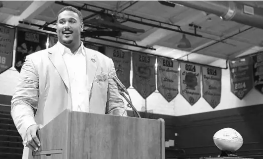  ?? CHARLES KING/STAFF PHOTOGRAPH­ER ?? Former Lake Highland Prep offensive lineman Max Starks presents the school with a golden football to commemorat­e Super Bowl 50.