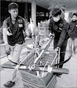  ?? Photo: AFP ?? Police officers push a basket containing bows as they search for any remaining dangerous explosives and chemicals at the Hong Kong Polytechni­c University in the city’s Hung Hom district on Thursday.