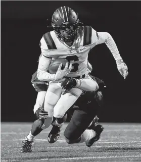  ?? Tim Warner / Contributo­r ?? Tompkins’ Marquis Shoulders (6) tries to get past Travis’ John Henderson (34) in the first half of a playoff game Thursday at Mercer Stadium.