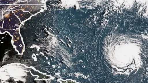  ?? — AFP/AP ?? Here it comes: An NOAA/RAMMB satellite image taken on Monday shows Hurricane Florence off the US east coast in the Atantic Ocean as Brian Franklin (below) prepares more generators for sale as people buy supplies at The Home Depot in Wilmington, North Carolina.