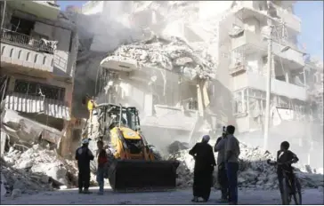  ?? THAER MOHAMMED/AFP ?? Civilians watch as a tractor clears the rubble following Syrian government forces airstrikes in the rebel held neighbourh­ood of Tariq a-Bab in Aleppo on Saturday.