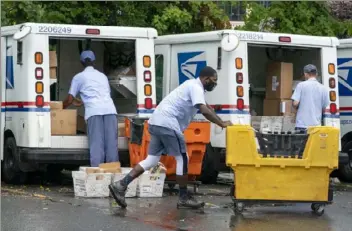  ?? Associared Press ?? Letter carriers load mail trucks for deliveries at a U.S. Postal Service facility in McLean, Va., in late July.