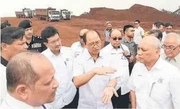  ??  ?? Tangau (centre) discusses with officers during his visit to the bauxite mining area in Felda Bukit Goh. — Bernama photo
