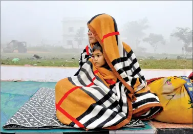  ?? REUTERS ?? A woman and her son are wrapped in a blanket as they sit on a pavement on a cold winter morning on the outskirts of Agartala, on Thursday.