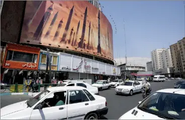  ?? ASSOCIATED PRESS PHOTO ?? Vehicles drive past an anti-Israeli banner showing missiles being launched on Friday in a square in downtown Tehran, Iran.