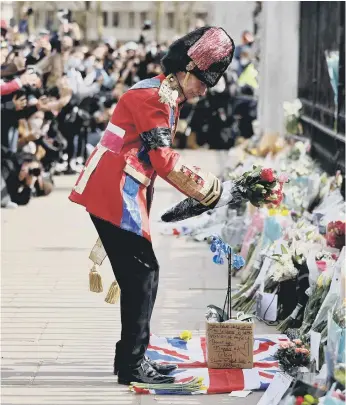  ??  ?? An ardent Royal fan lays a floral tribute at the front of Buckingham Palace.