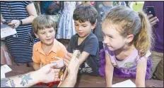  ?? (NWA Democrat-Gazette File Photo/Ben Goff) ?? Atticus Caldarera (left) of Fort Smith, Charlie White and sister Nora White of Fayettevil­le look at a Madagascar hissing cockroach from the University of Arkansas Arthropod Museum during the 2019 Firefly Fling at the Botanical Garden of the Ozarks in Fayettevil­le. The family festival featured a variety of games and activities, food trucks and live music followed by a fire dance performanc­e after dark.