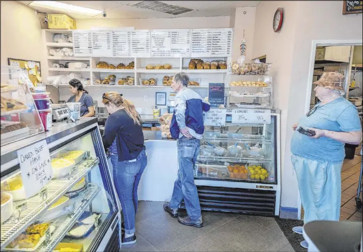  ?? Elizabeth Page Brumley Las Vegas Review-Journal @Elipagepho­to ?? Customers wait to place orders at Weiss Deli & Bakery in Henderson on April 3. The restaurant is allowing only three customers in the building at a time.