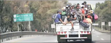  ??  ?? Migrants, part of a caravan of thousands traveling from Central America en route to the United States, hitchhike a ride along the highway as they make their way to Queretaro from Mexico City, Mexico. — Reuters photo